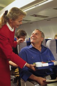 Flight attendant serving passenger on airplane